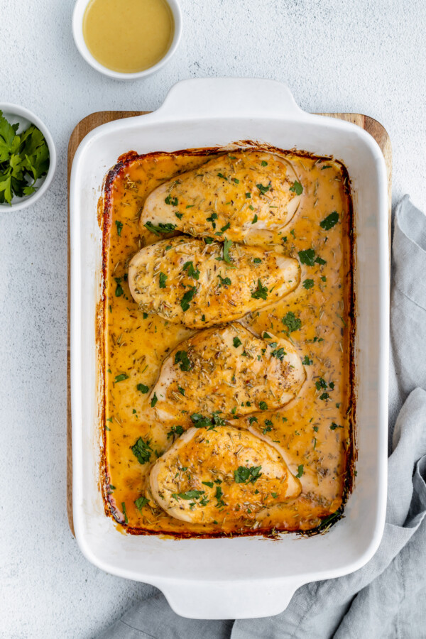 Baked chicken in a white baking dish.