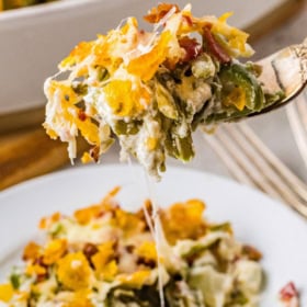 A fork picking up a bite of creamed green bean casserole off a plate.