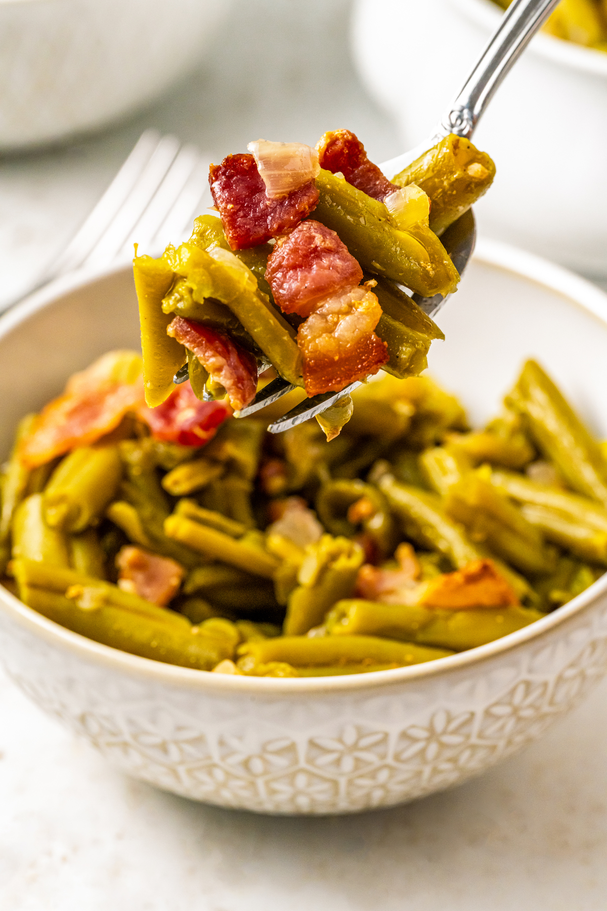 Lifting a bite of crock pot green beans toward the camera.