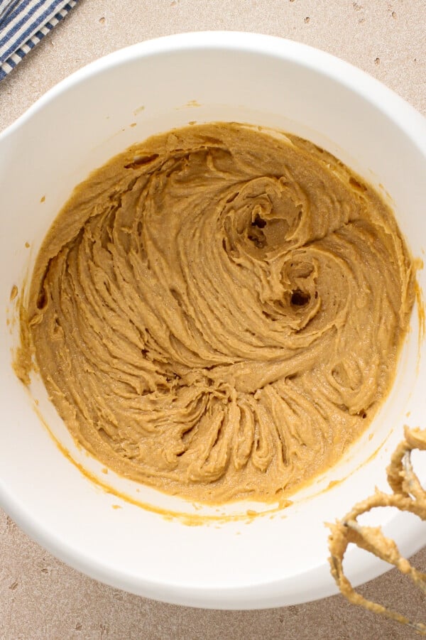 Peanut butter, butter, brown sugar and granulated sugar being beaten together with a hand mixer.